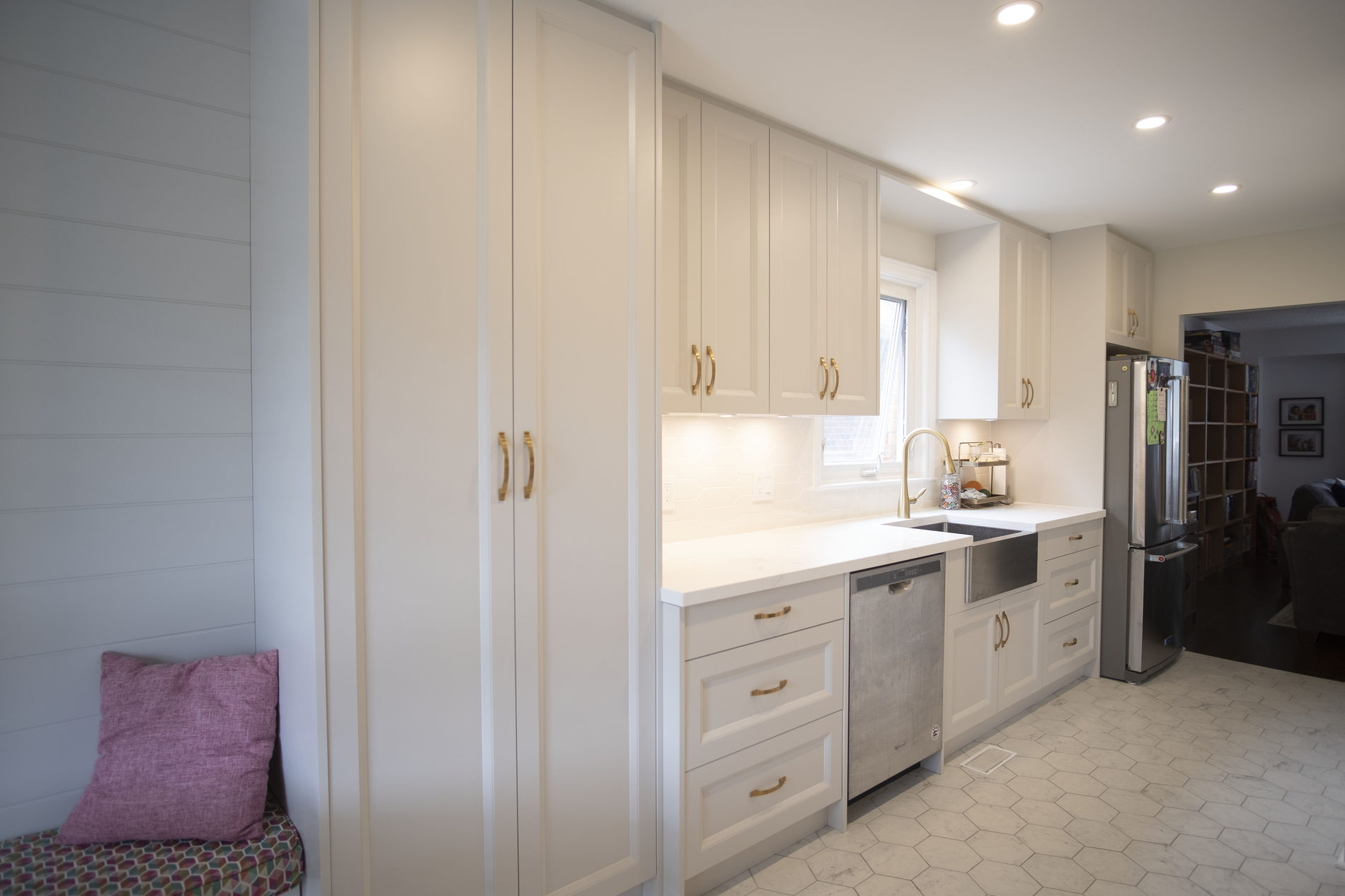 White kitchen island with bench seating in an Etobicoke renovation by Studio Kimi