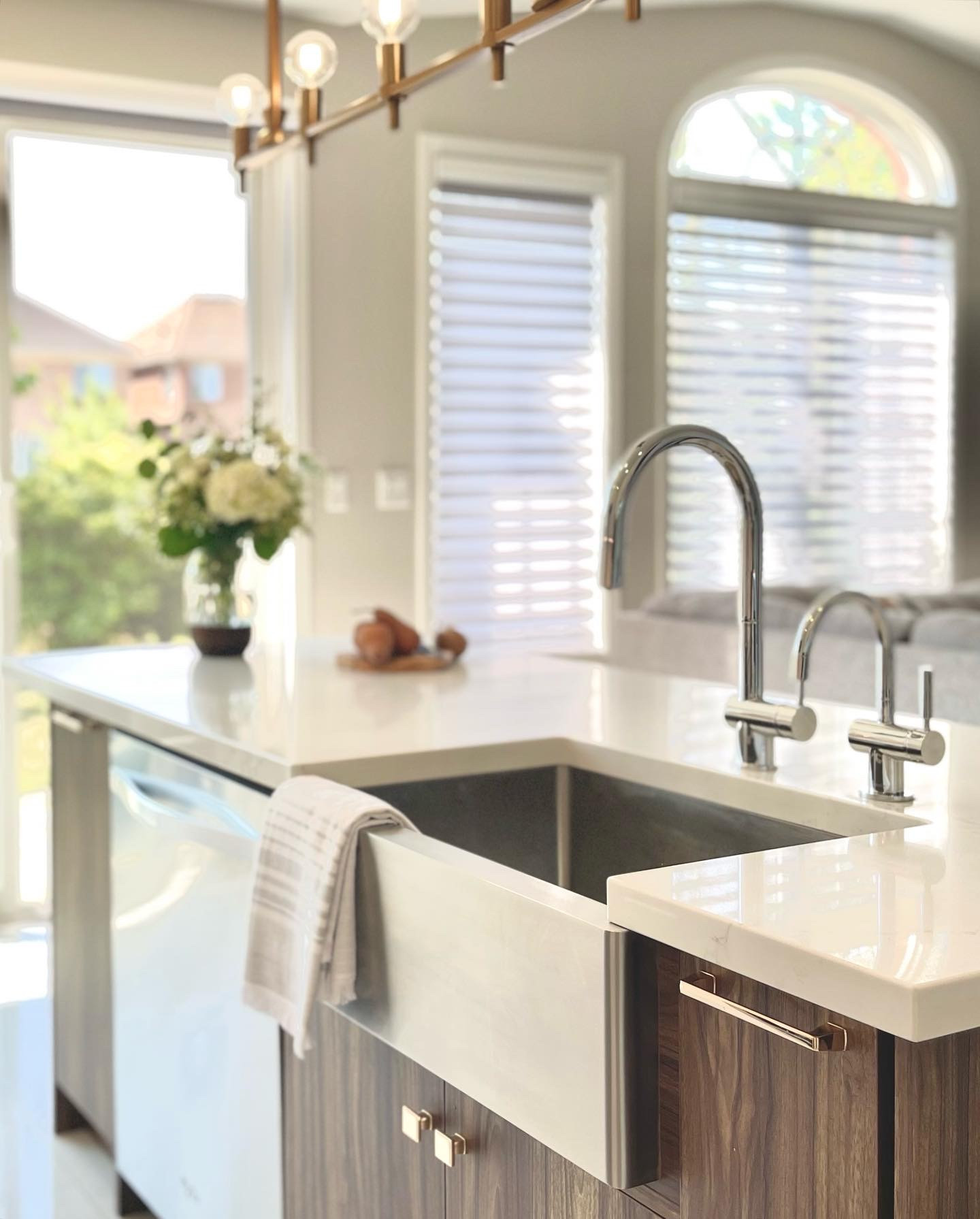 Farmhouse sink under an arched window with marble counter