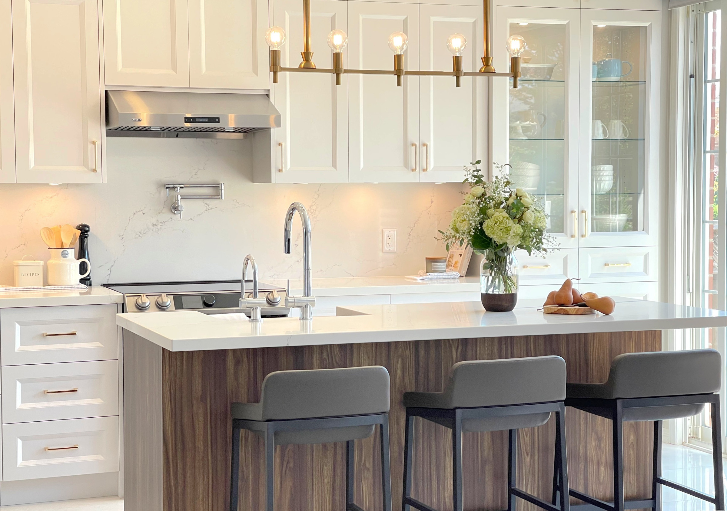 Open white kitchen with walnut island and brass lighting, Mississauga